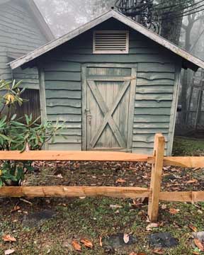 little blue garden shack with fence before it