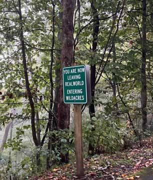mountain path sign that reads you are now leaving real world entering wildacres
