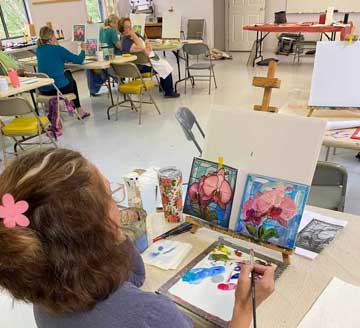people working on paintings in a classroom