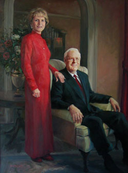 portrait of a standing woman wearing red and a seated man