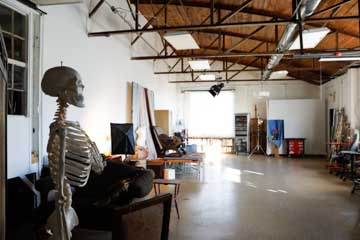 large open artist's studio with skeleton, rafters and window light shining on floor